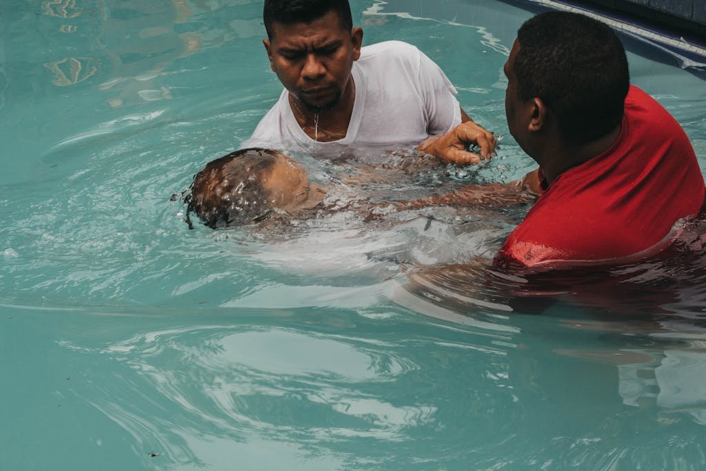 A meaningful baptism ceremony with two adults in a swimming pool, showcasing faith and community.